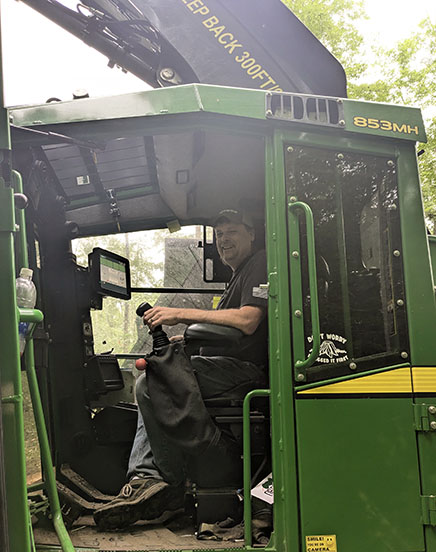 Charlie Harris, owner of Northern MI Forestry, in cab of John Deere harvester at job site